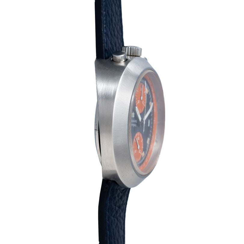 Stainless steel chronograph watch with orange and black dial on dark blue leather strap.