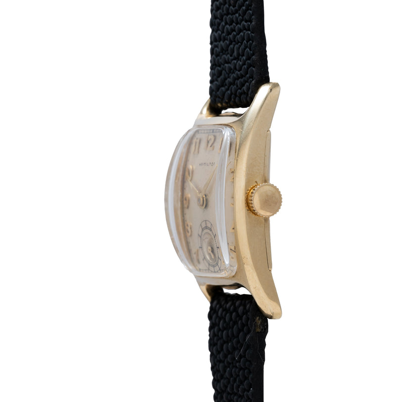 Hamilton Boulton vintage watch with rectangular cream dial, gold-tone case, and black fabric strap.