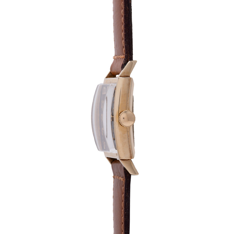 Gold-tone watch with rectangular dial and brown leather strap shown from the side view.