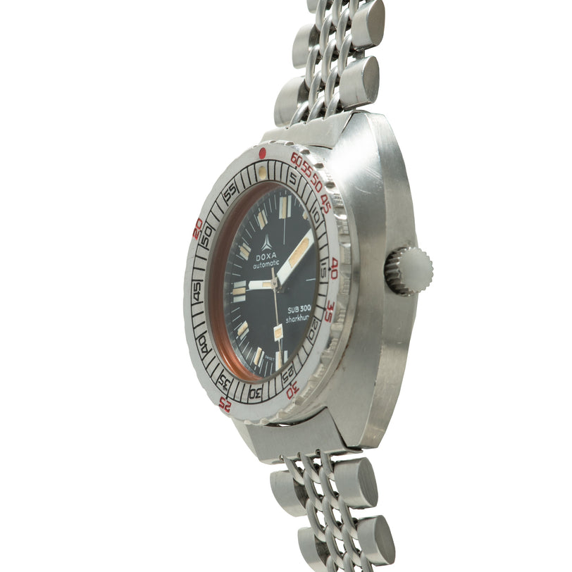 Silver dive watch with black dial, hour markers, red bezel text, and stainless steel bracelet.