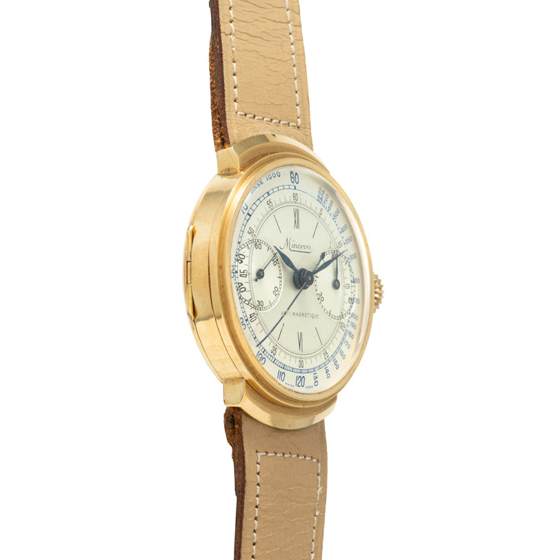 Gold-tone chronograph watch with cream dial, Roman numerals, and tan leather strap with white stitching.
