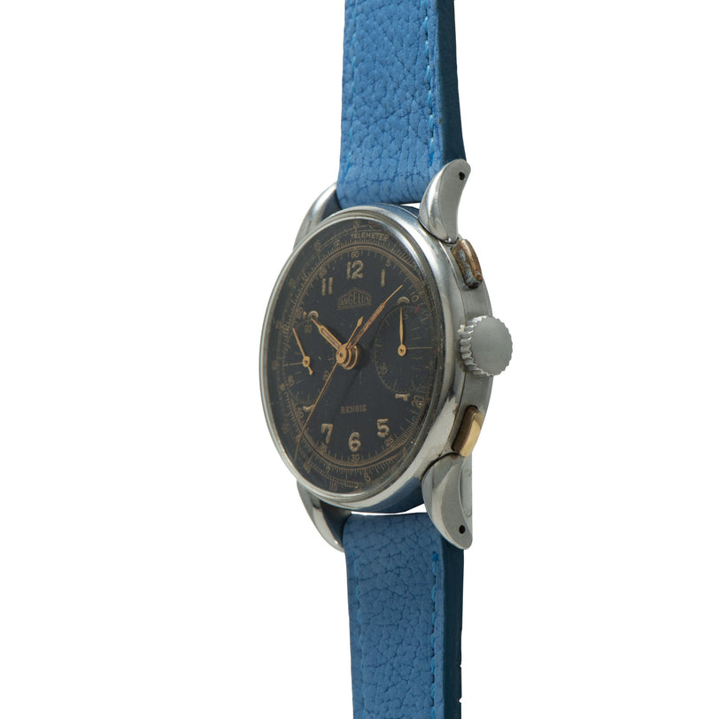 Angelus chronograph watch with dark dial, gold numerals and hands, metal case, and blue textured leather strap.