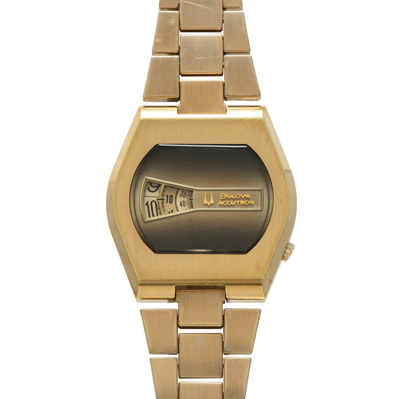 Gold-tone Bulova Accutron watch with rectangular direct-read dial display and matching link bracelet.