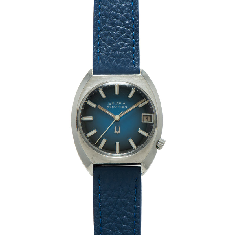 Bulova Accutron watch with blue dial, silver-tone case, blue leather strap, and date window.