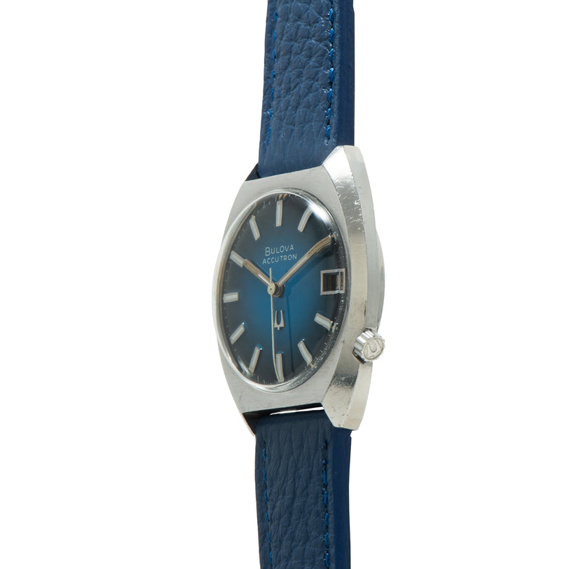 Bulova Accutron watch with blue gradient dial, silver case, hour markers, date window, and blue leather strap.