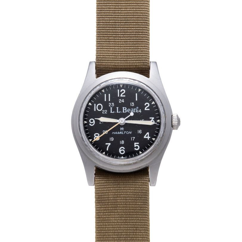 Hamilton Khaki Field mechanical watch with black dial, Arabic numerals, and tan fabric strap.