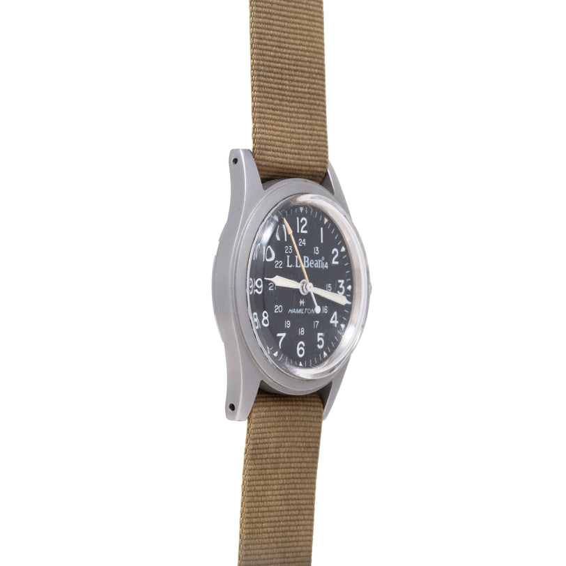 Hamilton Khaki Field mechanical watch with black dial, Arabic numerals, and tan fabric strap.