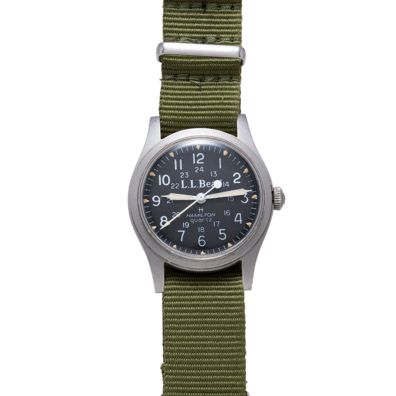 Hamilton Khaki Field Quartz watch with dark dial, Arabic numerals, and olive green fabric strap.