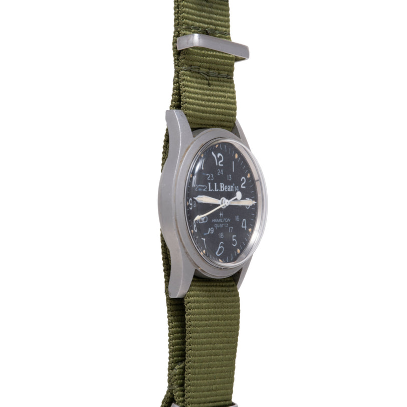 Hamilton Khaki Field Quartz watch with black dial, silver case, and olive green fabric strap.