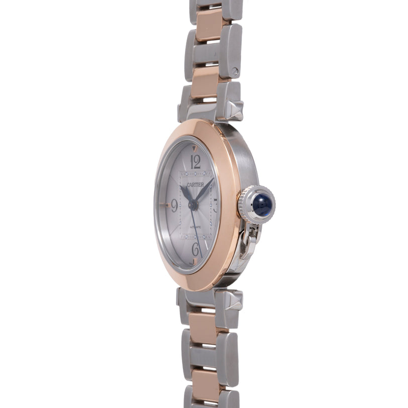 Two-tone stainless steel and rose gold watch with oval dial, Arabic numerals, and crown with blue sapphire.