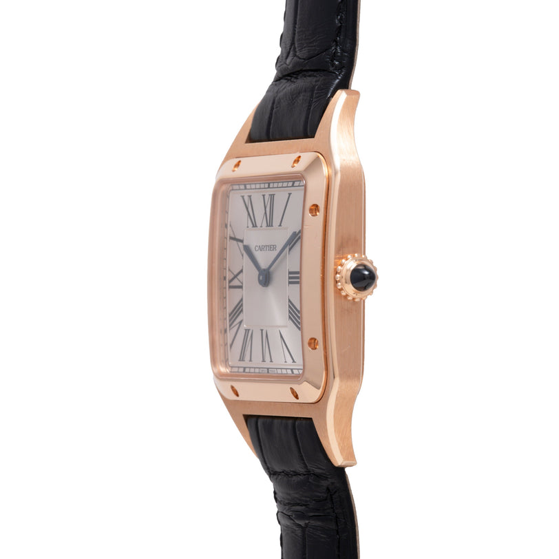 Rose gold rectangular watch with silver dial, Roman numerals, black leather strap, and crown with black stone.