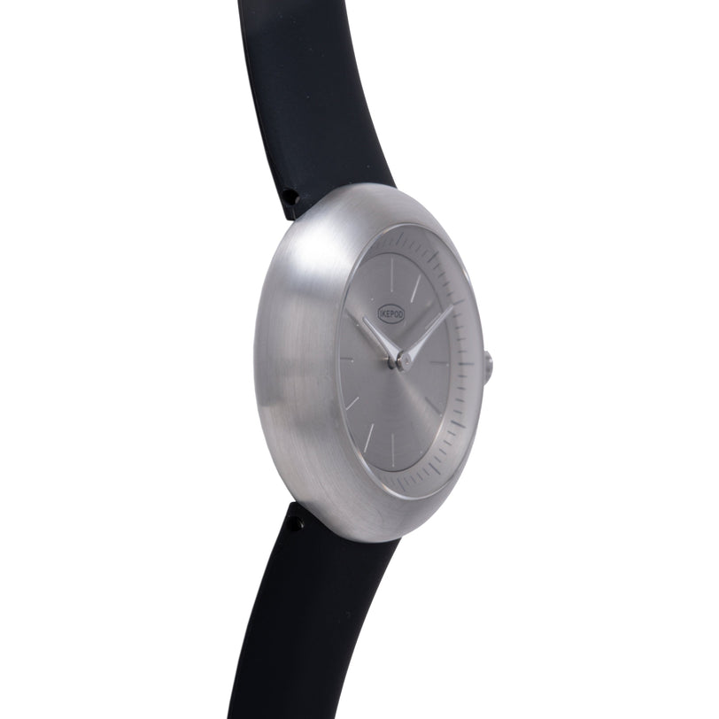 Brushed silver watch with minimalist dial, hour markers, and black rubber strap.