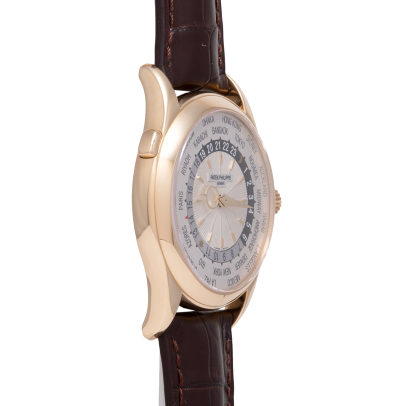 Rose gold watch with cream dial featuring world city names around outer ring and dark leather strap.