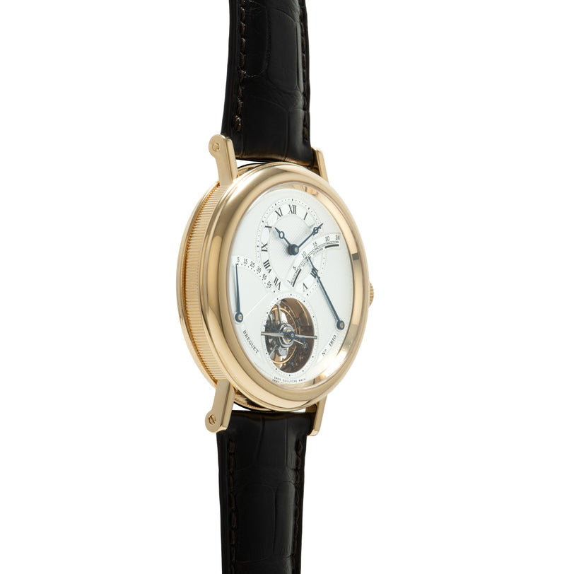 Gold-tone watch with white dial, Roman numerals, visible tourbillon at 6 o'clock, and black leather strap.