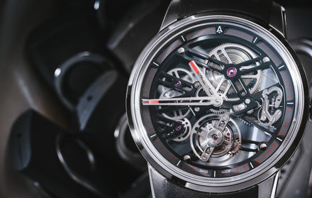 A close up of a watch face with exposed gears and mechanisms and a small capital A logo and the text Swiss Made