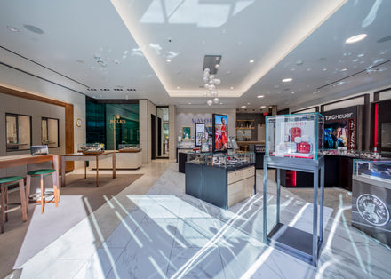 A luxury jewelry and watch store interior with bright lighting, glass displays, and branded sections.