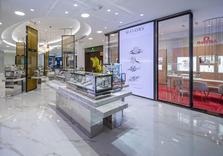 Modern jewelry store interior with glass display cases, marble floor, and bright lighting.
