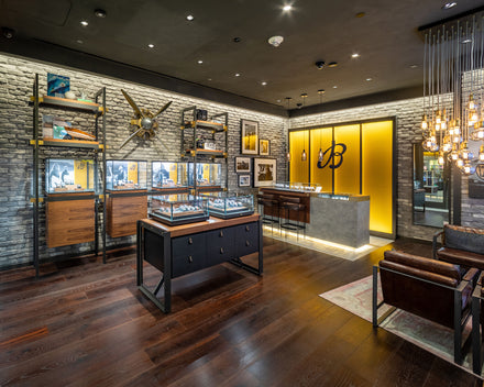 Modern jewelry store interior with glass display cases, industrial decor, and warm lighting.