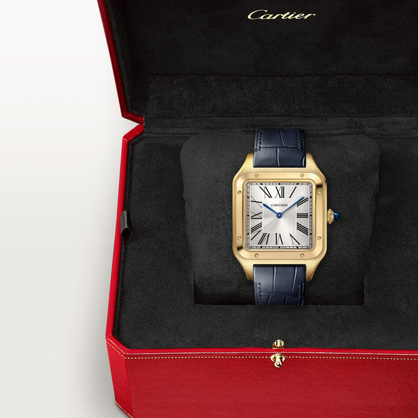 A Cartier Santos Dumont gold watch with a blue leather strap, displayed in a red Cartier box.