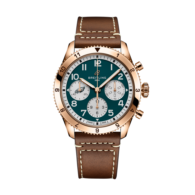 Breitling Classic Avi Chronograph 42 NFL Philadelphia Eagles Edition with a gold case, brown leather strap, and green dial displayed on a black background.