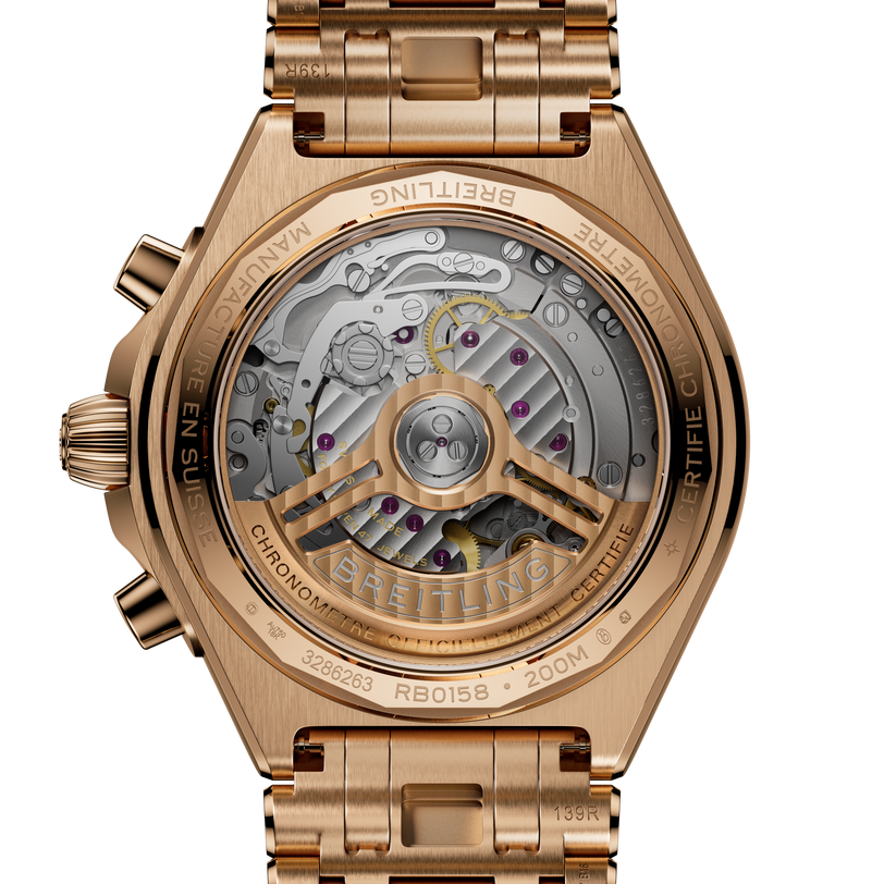 Gold-tone chronograph watch with visible mechanical movement through transparent case back and matching bracelet.