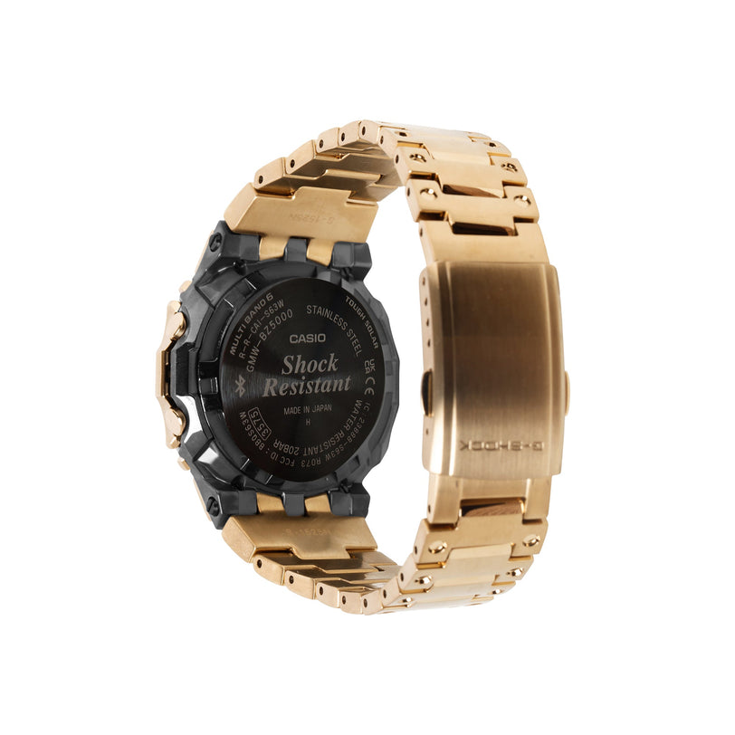 Gold stainless steel digital watch with black resin case and link band, shown from back view displaying shock resistant marki