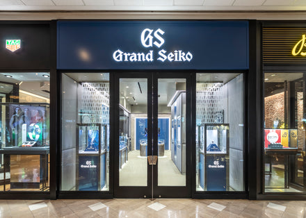 Grand Seiko store entrance with glass doors and illuminated signage in a shopping mall.