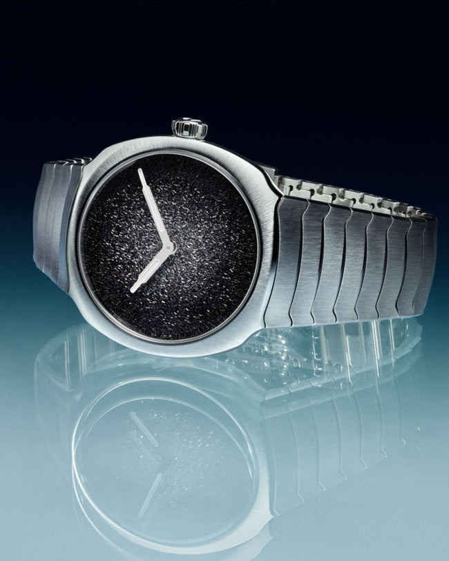 Silver-tone watch with black textured dial, white hands, and segmented metal bracelet band.