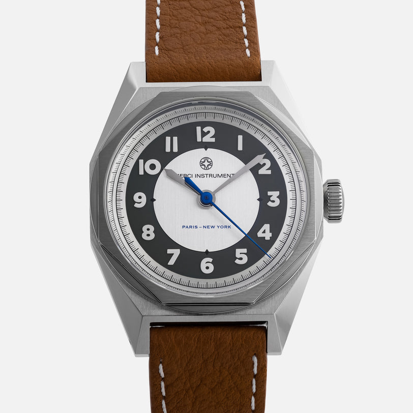 The Merci INSTRUMENTS Beaumarchais H02 Limited Edition For Hodinkee by Merci features a silver case, brown leather strap, black and white dial, and blue hands.