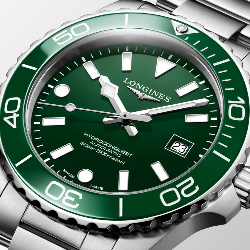 Longines watch with green dial and silver case on a light gray background