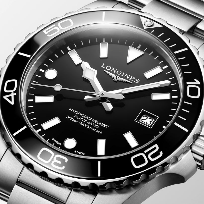 Longines watch with black dial and silver case on a light gray background