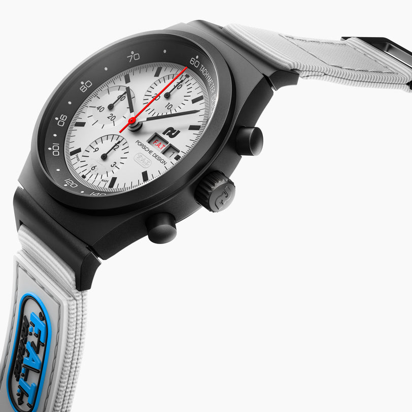 The Porsche Design Chronograph 1 F.A.T 2025 Edition features a black and white dial, a white strap, and a visible blue patch, showcased on a white background.