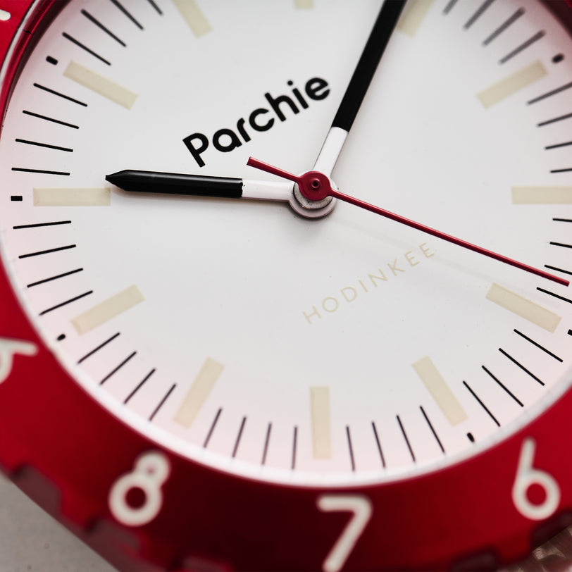 Close-up of the Parchie Lunar-Time Limited Editions for Hodinkee 36, featuring a red bezel, white face, and Parchie and Hodinkee branding on the dial.