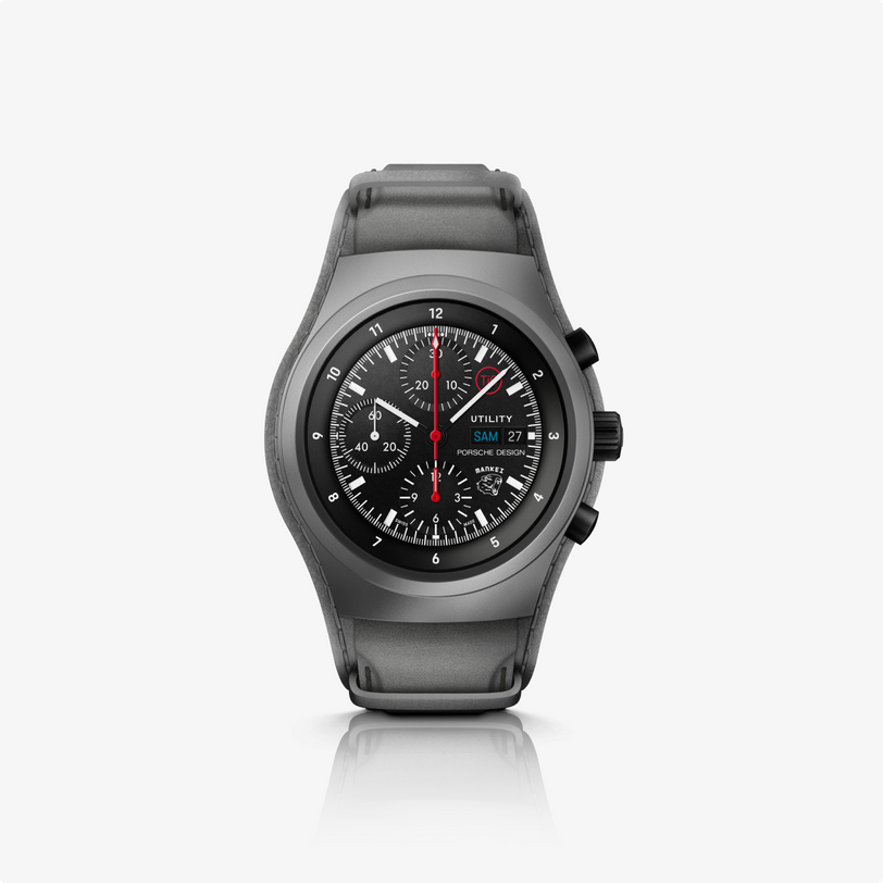 The Porsche Design Chronograph 1 Utility Limited Edition is a black and gray round-faced chronograph wristwatch with a black strap, displayed on a white background.