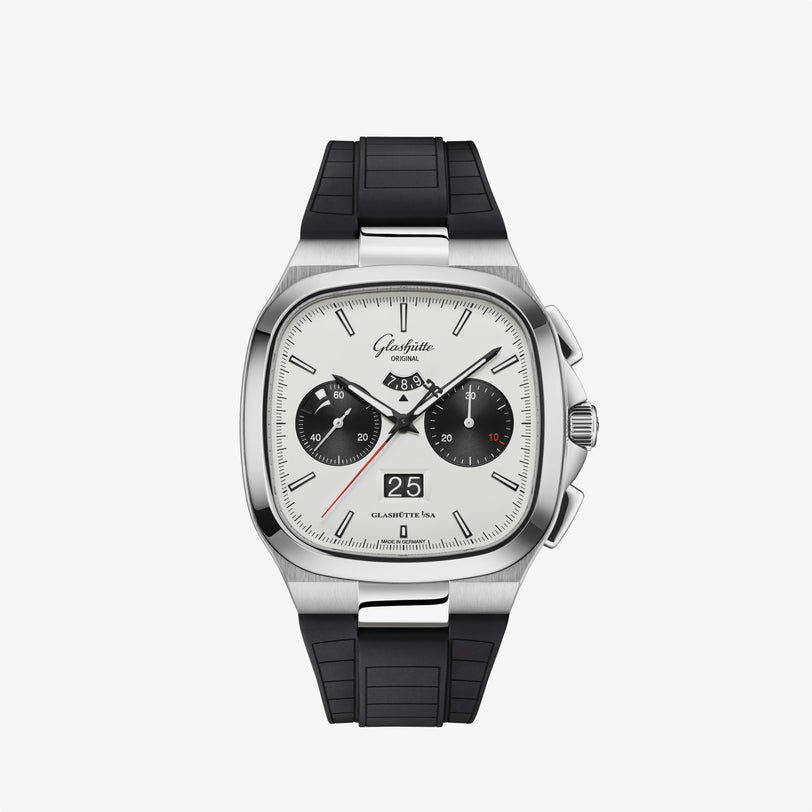 The Glashütte Original Seventies Chronograph Panorama Date is a silver and black wristwatch with a square face and black rubber strap, shown on a white background.