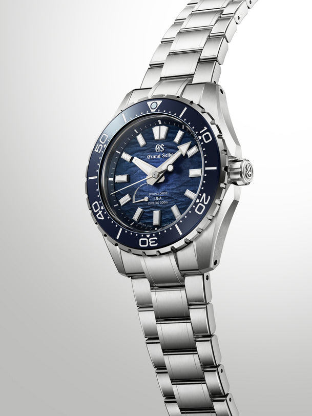 Silver and blue dive watch with dark blue dial, white hour markers, and matching blue rotating bezel on stainless steel brace