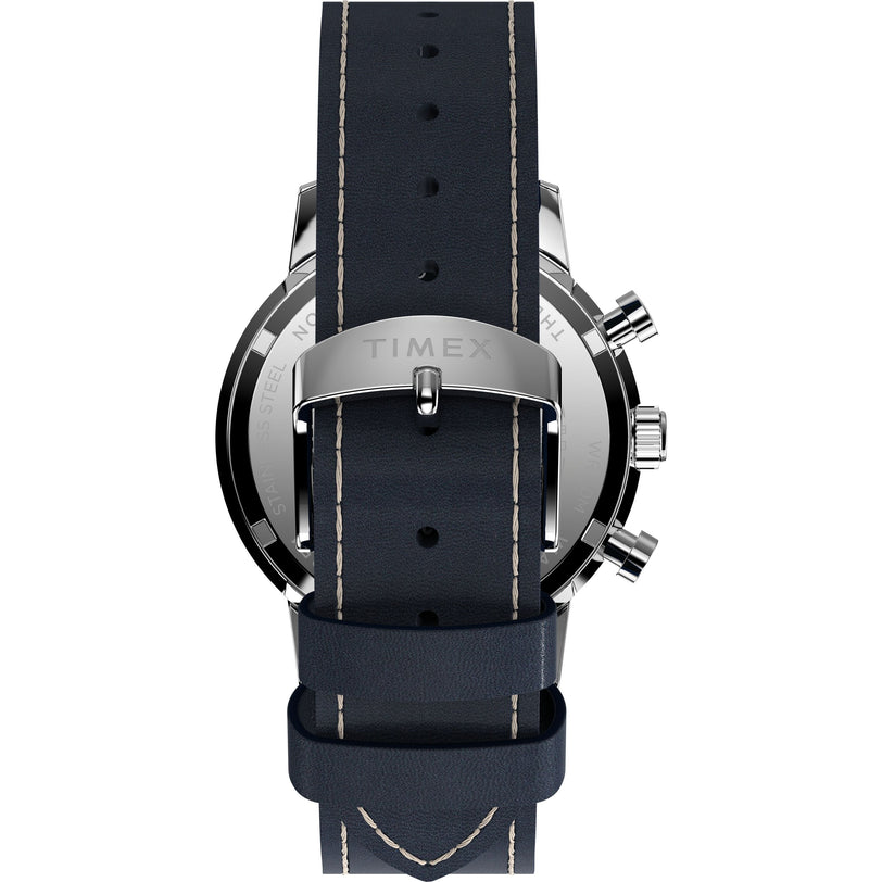 A close-up of the Marlin® Chronograph Tachymeter by Timex shows its stainless steel case back and dark blue leather strap with light stitching and a metal buckle engraved with TIMEX.