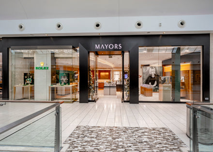 Mayors jewelry store with glass storefront, Rolex displays, and a large black-and-white poster inside.