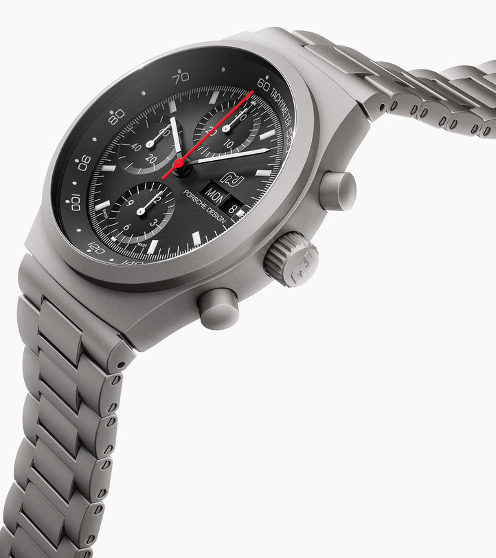 The Porsche Design Chronograph 1 1975 Limited Edition features a matte silver metal case, black dial, red second hand, and a linked bracelet band.