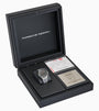 The Porsche Design Chronograph 1 1975 Limited Edition watch is shown in a black box with certification cards and documents beside it.