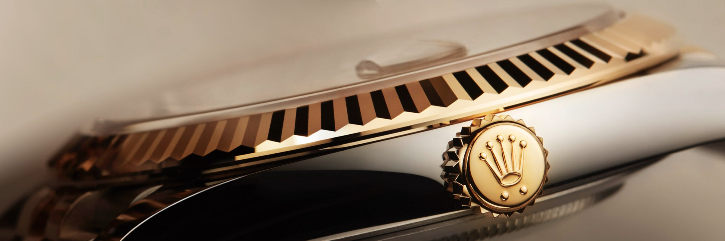 Close-up of a gold Rolex watch crown and bezel, highlighting the detailed craftsmanship and logo.