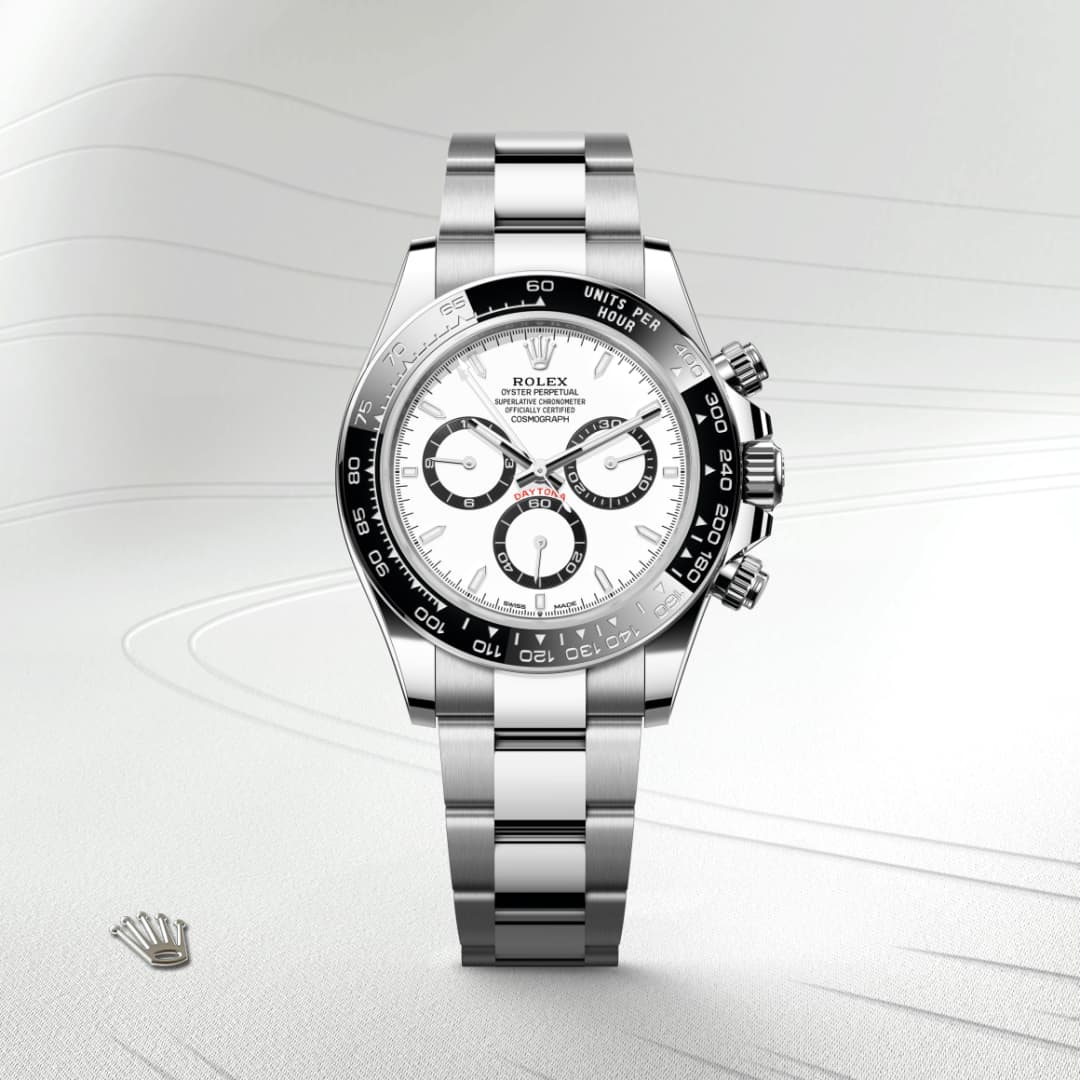 A silver Rolex Daytona watch with a white dial and black bezel displayed on a light textured background.