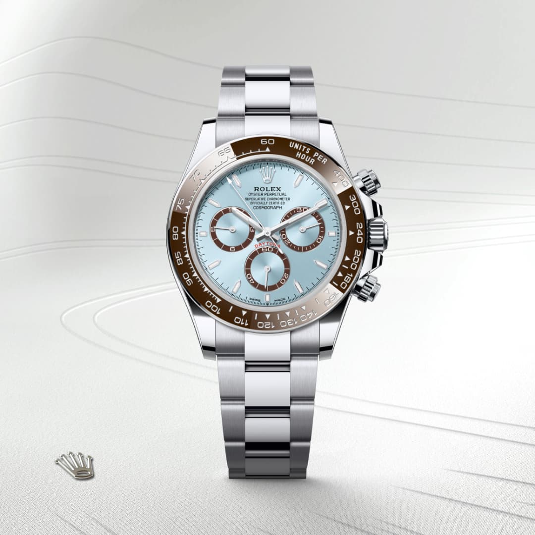 A Rolex watch with a silver band, light blue face, and brown bezel displayed on a light textured background.