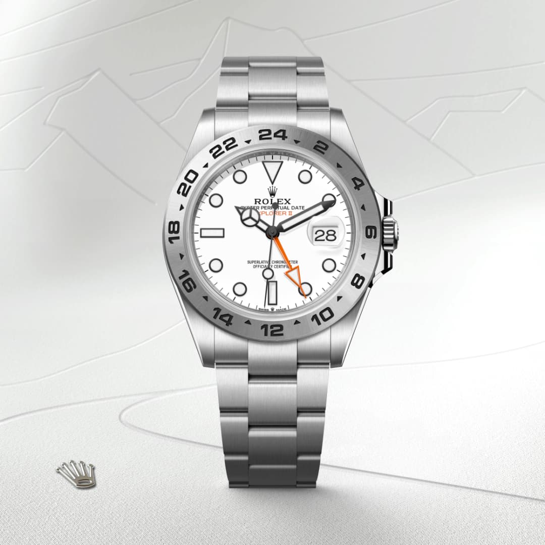 A stainless steel Rolex Explorer II watch with a white dial and orange 24-hour hand against a light background.