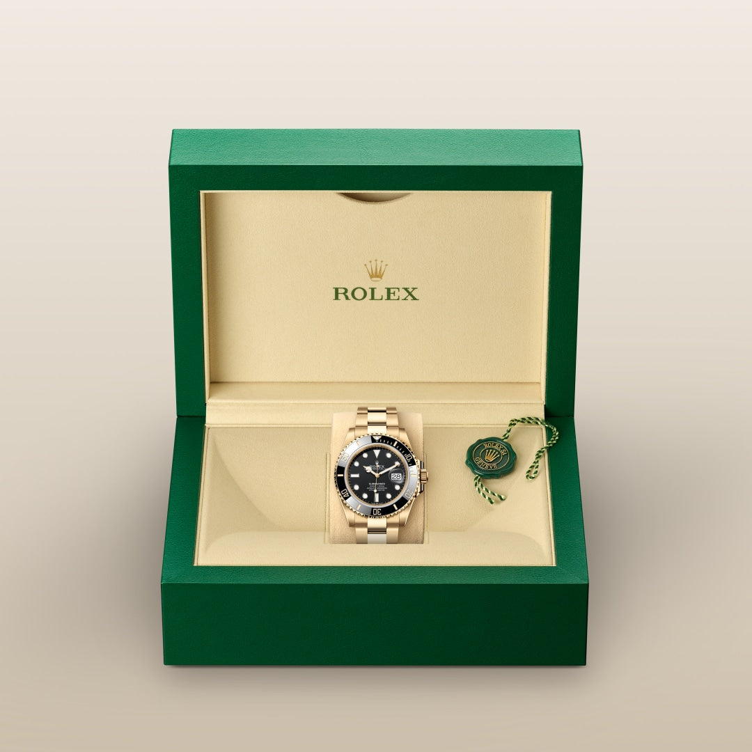 A gold Rolex watch with a black dial in an open green and beige Rolex box.