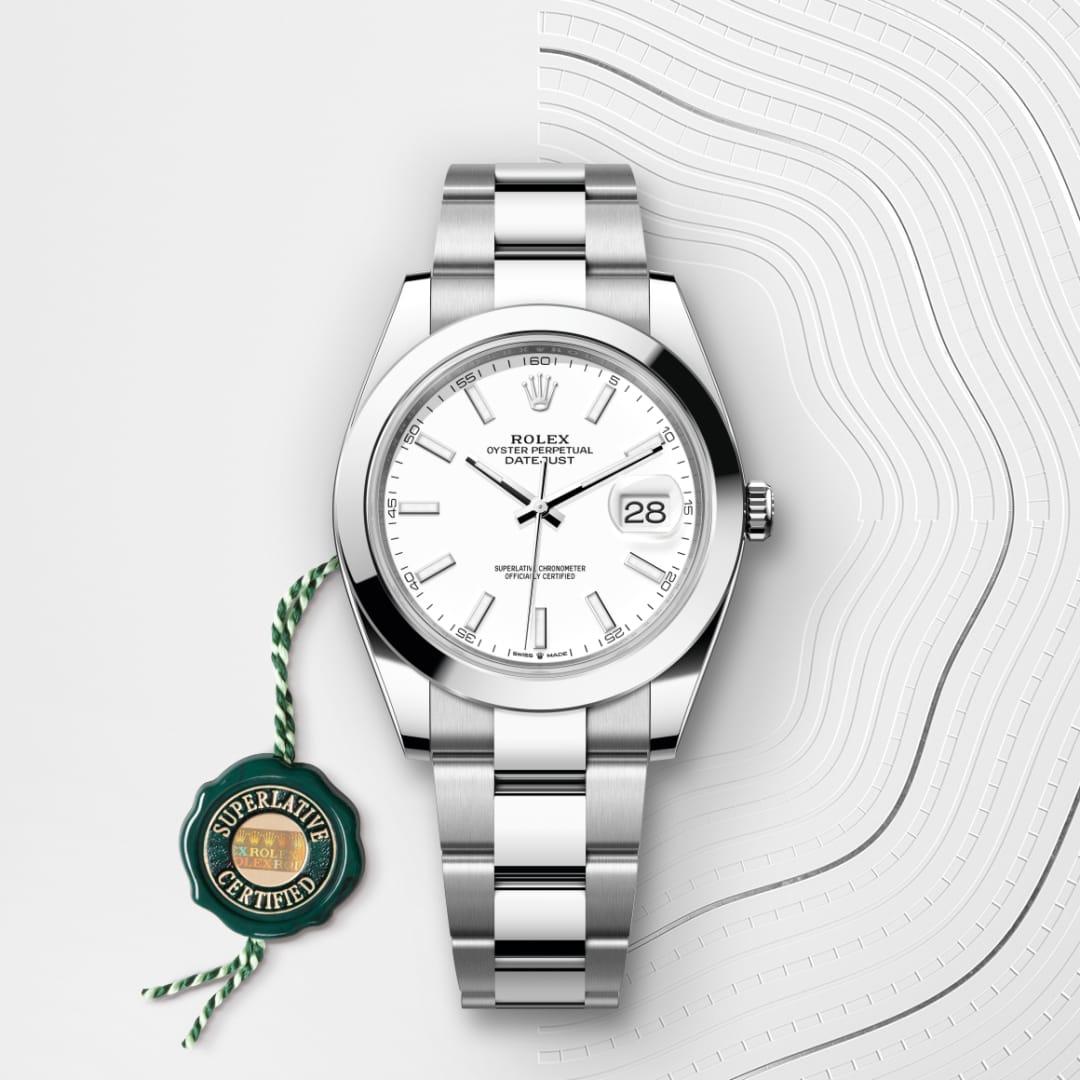 A silver Rolex Datejust watch with a white dial, green certification tag, and textured white background.