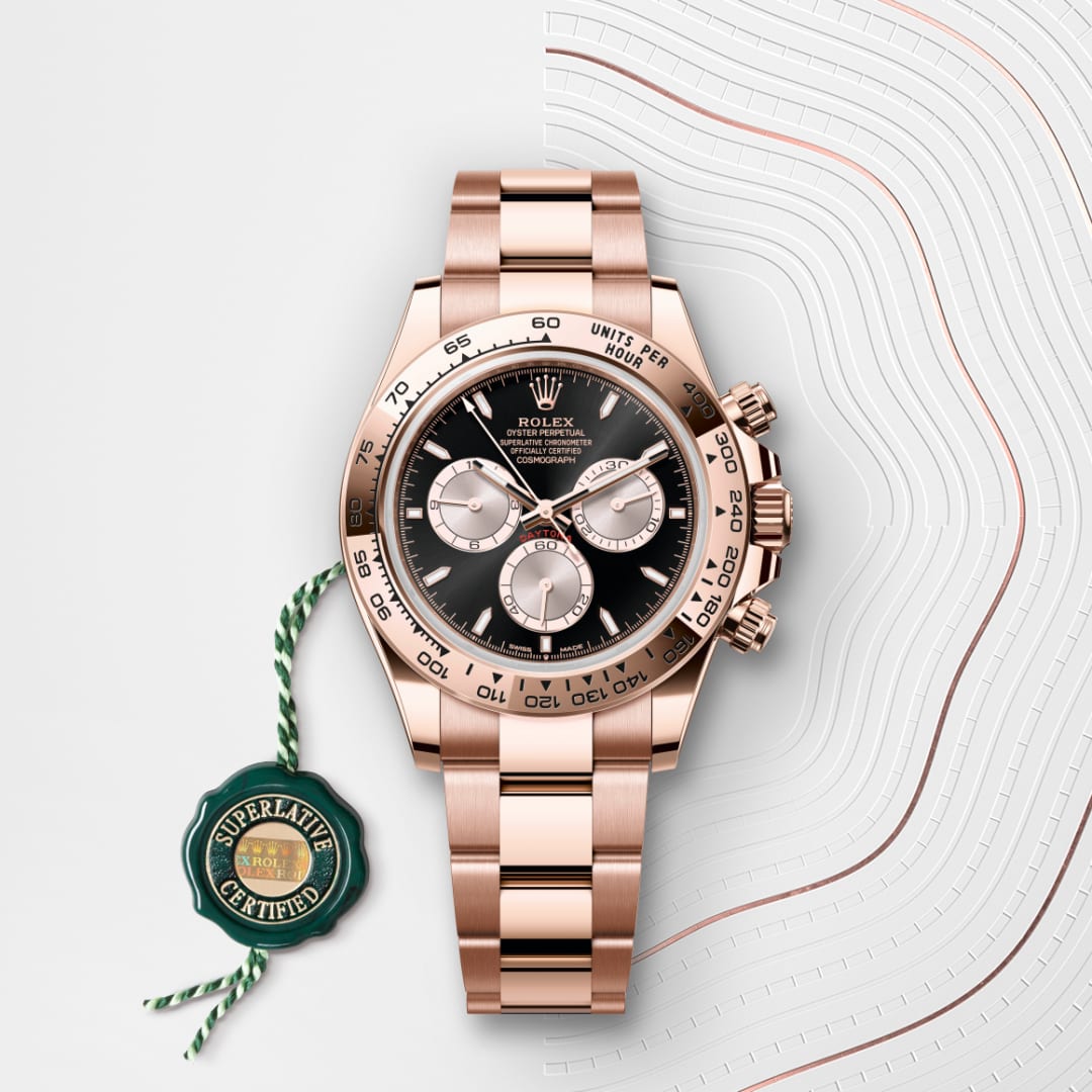 A rose gold Rolex watch with a black dial, three subdials, and a green Superlative Certified tag.