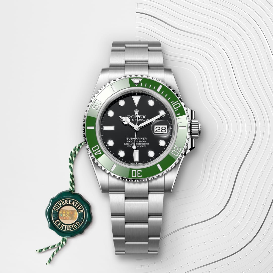 A Rolex Submariner watch with a green bezel and Superlative Certified tag on a textured white background.