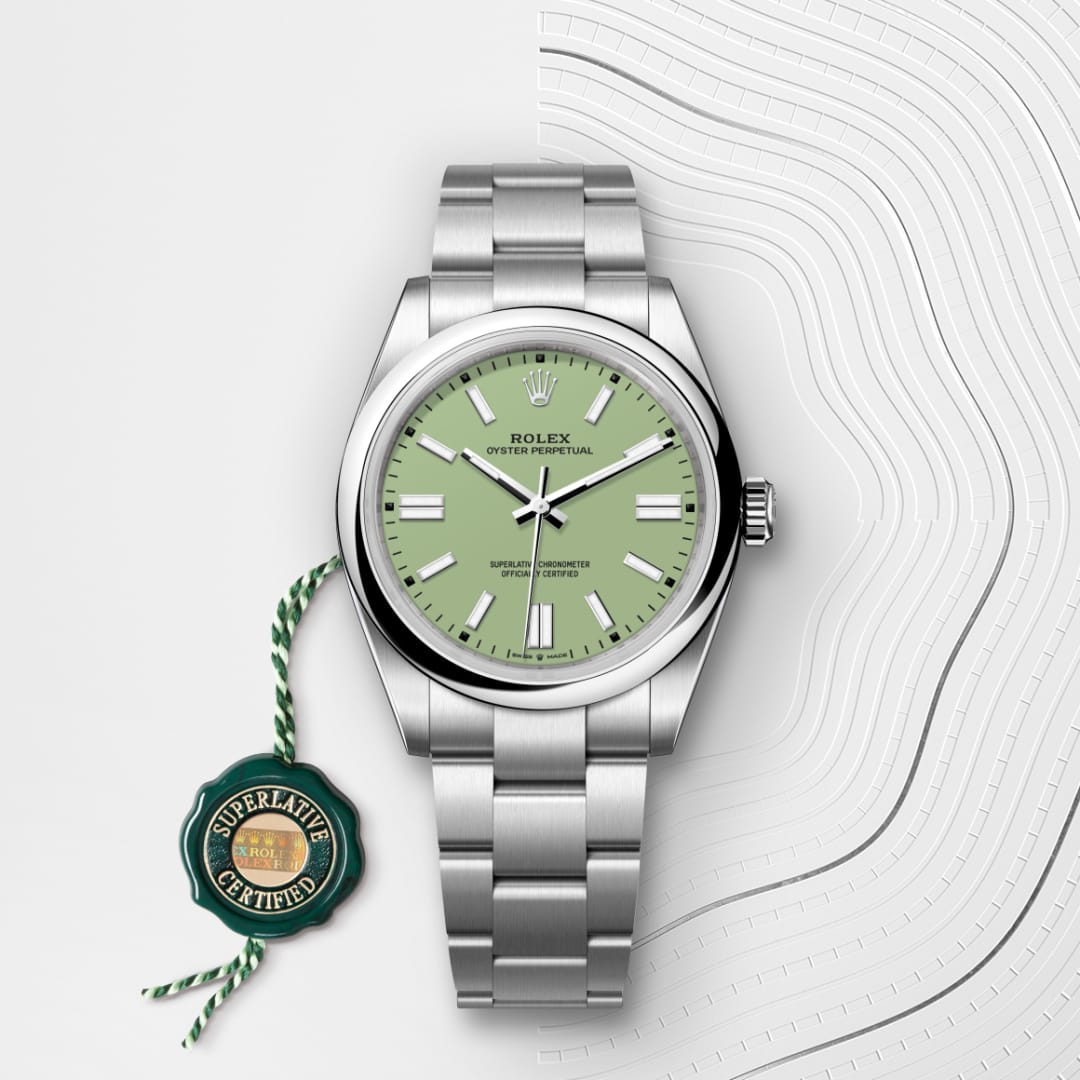 Silver Rolex Oyster Perpetual watch with a light green dial and certification tag on a white patterned background.