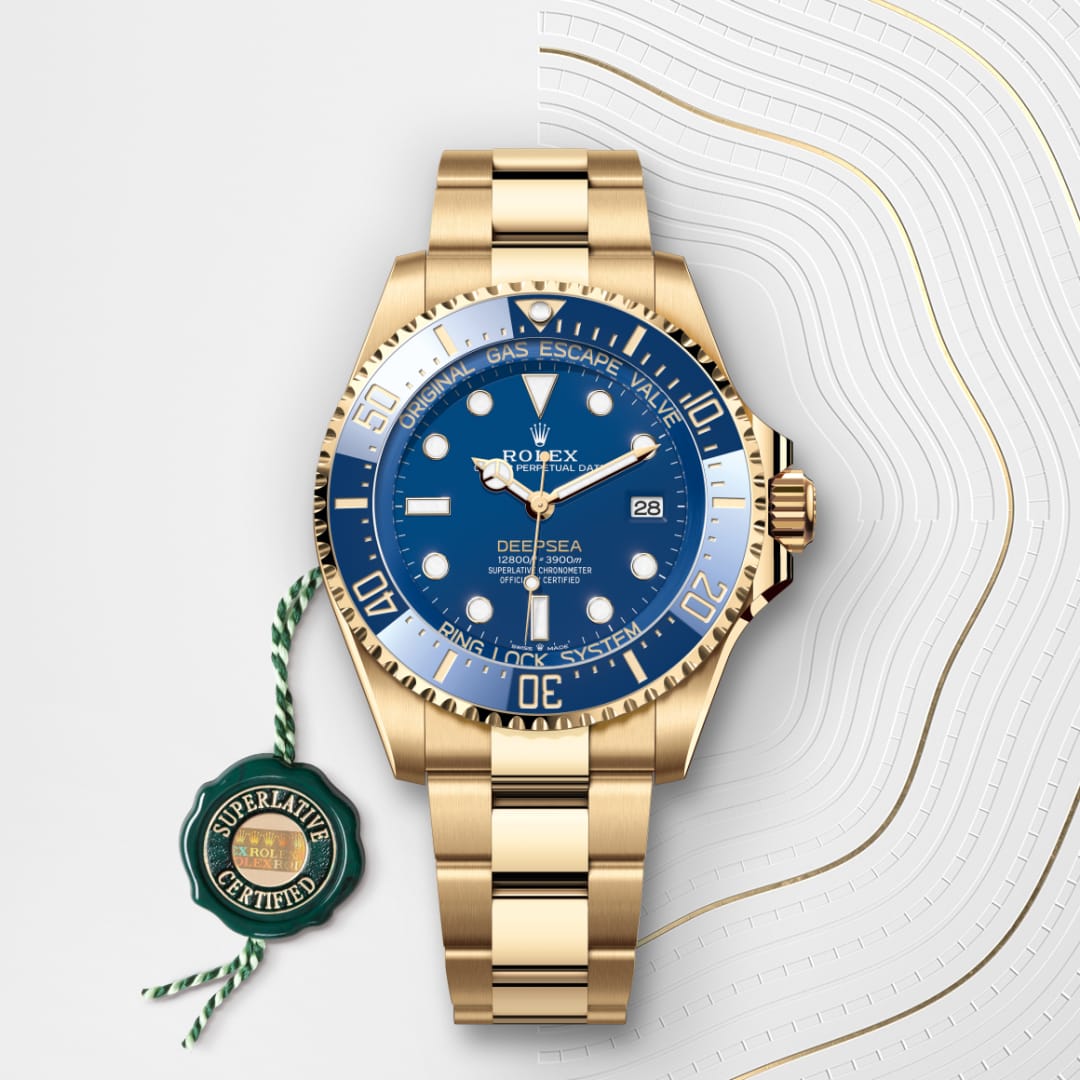 Gold Rolex Deepsea watch with blue dial and bracelet, beside a green Superlative Certified tag.